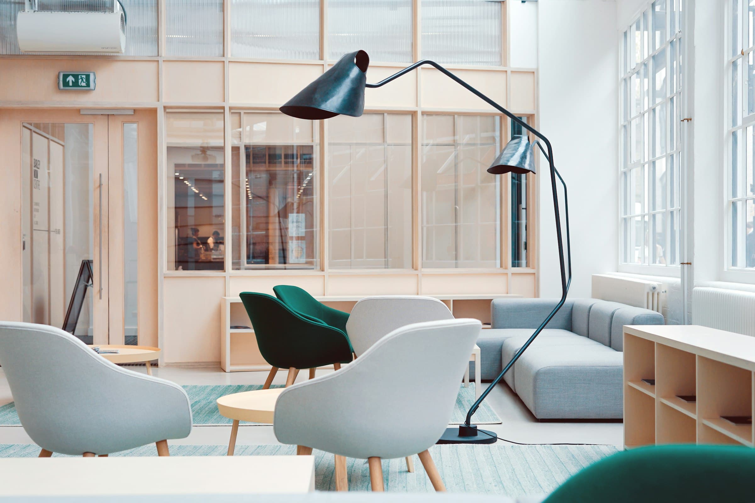 An empty, warmly lit lounge space with wood tones and an arc floor lamp.